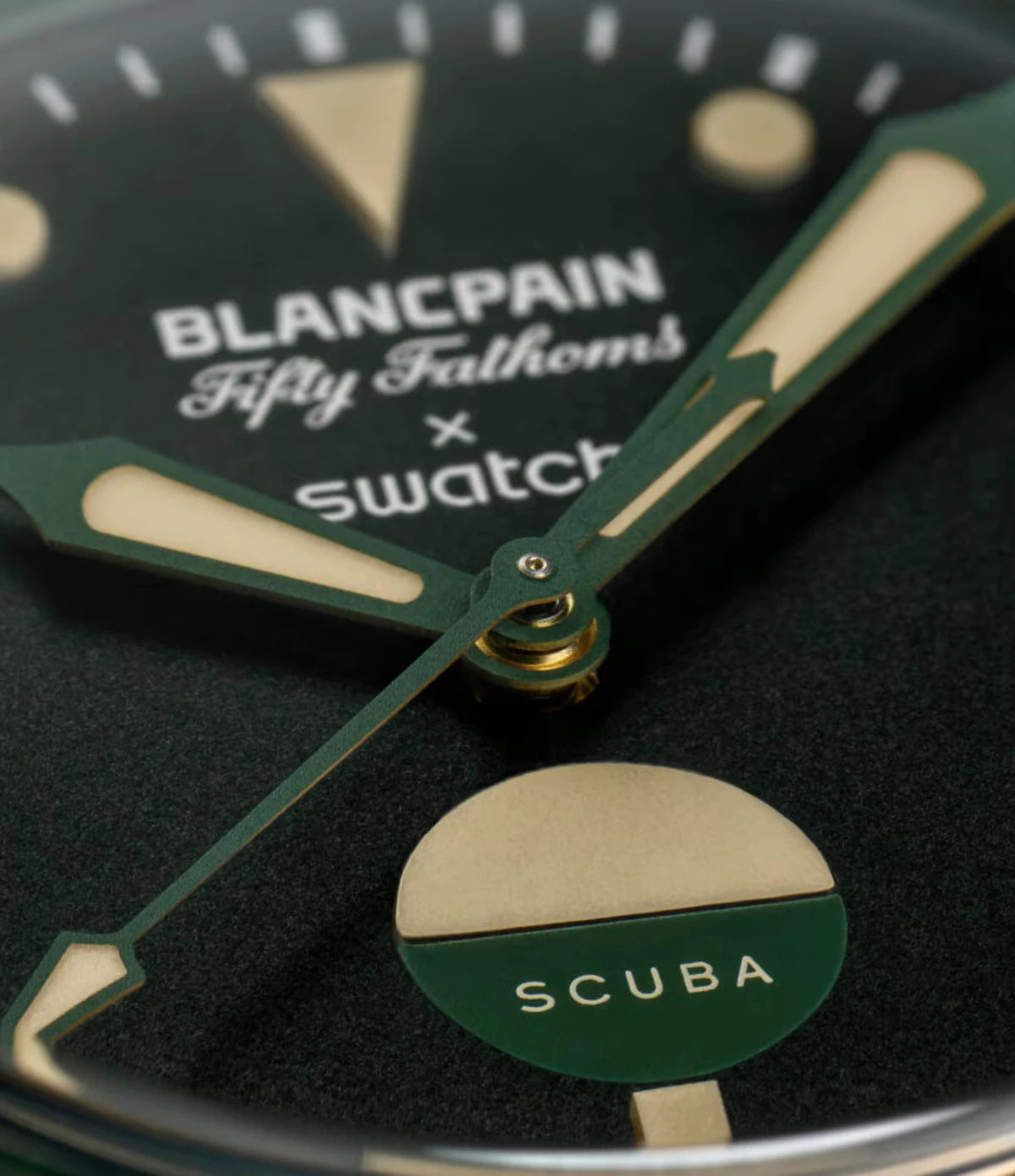 Close-up of the Blancpain X Swatch Green Abyss SO35G100 dial showing dark green hue, Super-LumiNova hour indexes and bicolor water contact indicator at 6 o'clock