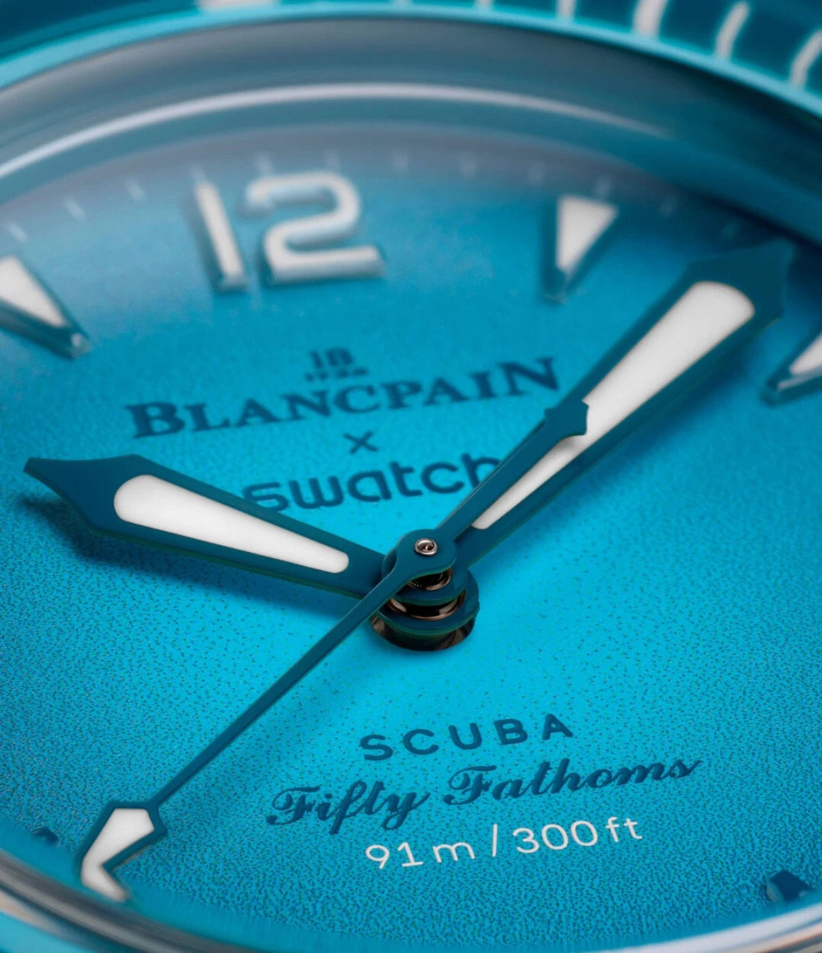 Close-up of the Blancpain X Swatch Blue Lagoon SO35L400 gradient turquoise-blue dial showing Super-LumiNova hour indexes and hands