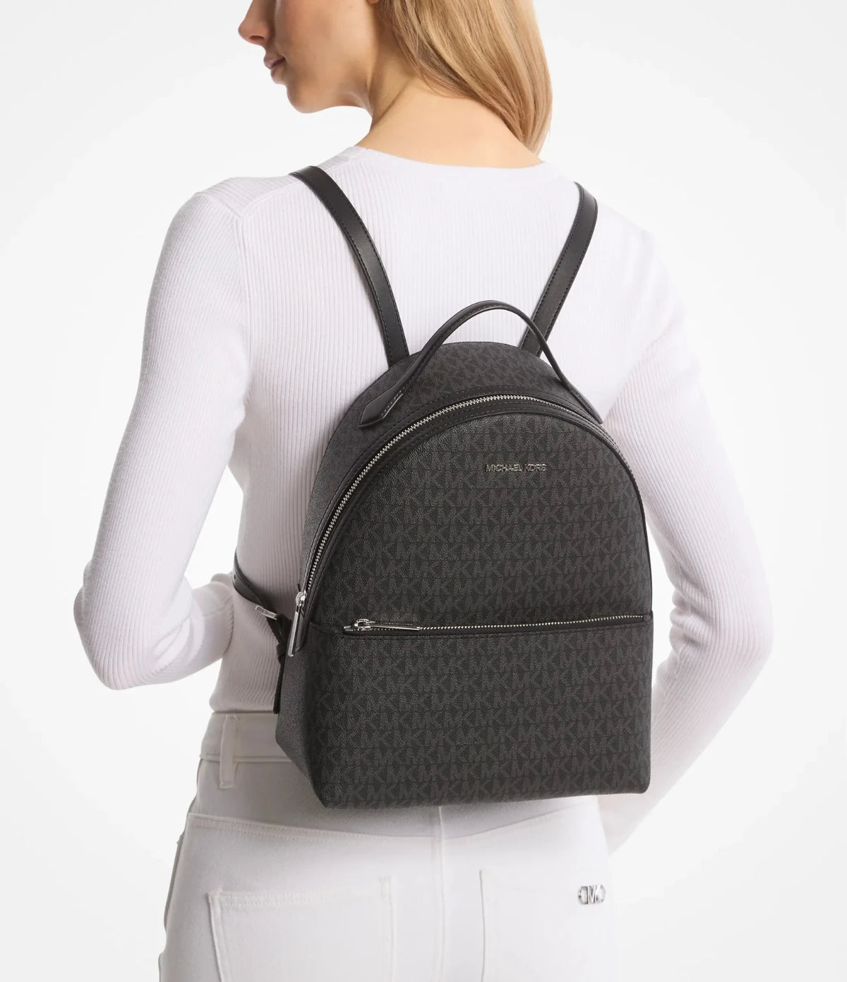 Woman wearing the Michael Kors Sheila Medium Signature Logo Backpack 35H3S6HB6B, styled for daily commuting and travel