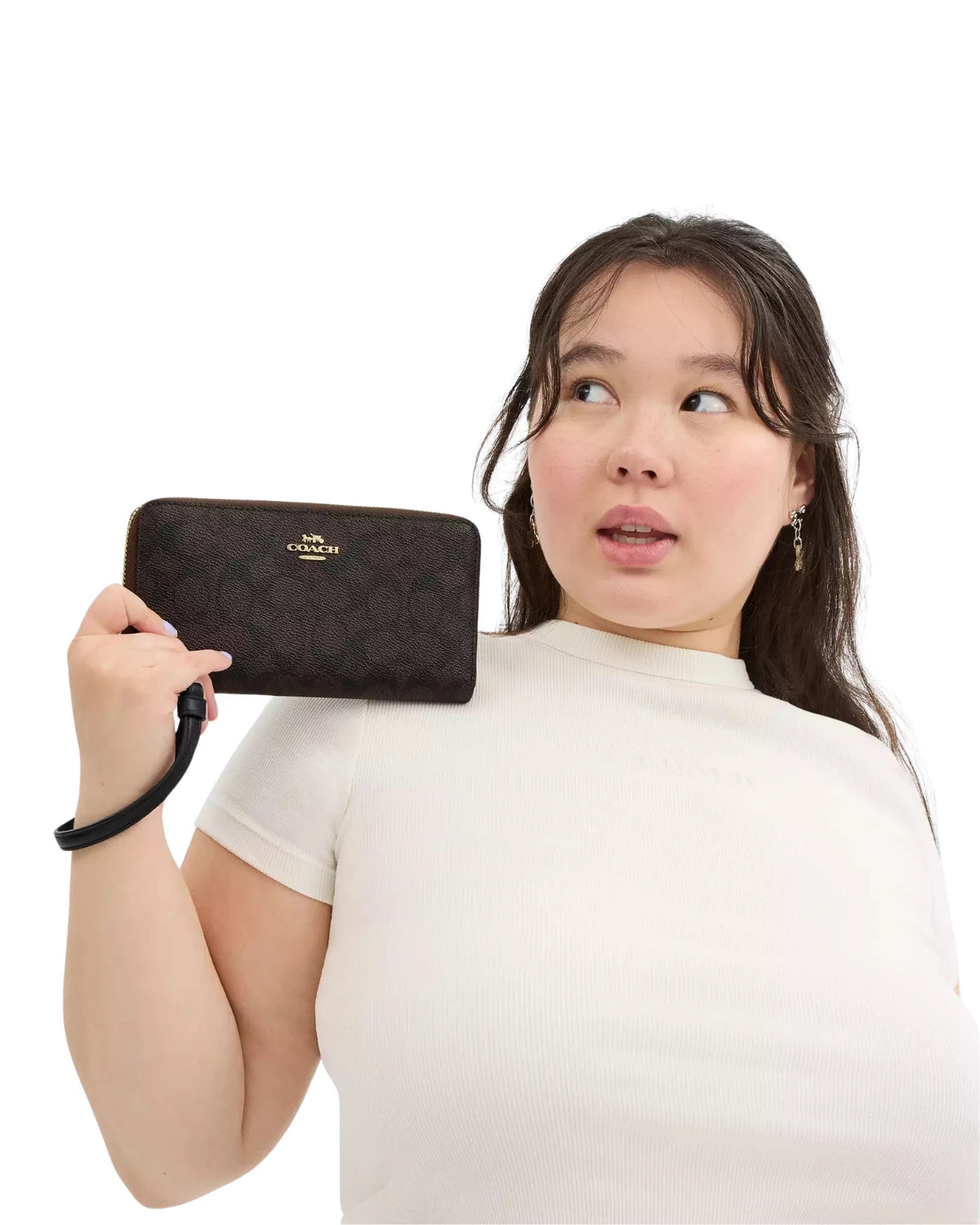 Woman holding the Coach Long Zip Around Wallet in Signature Canvas CW778 by its detachable wrist strap, styled for everyday use