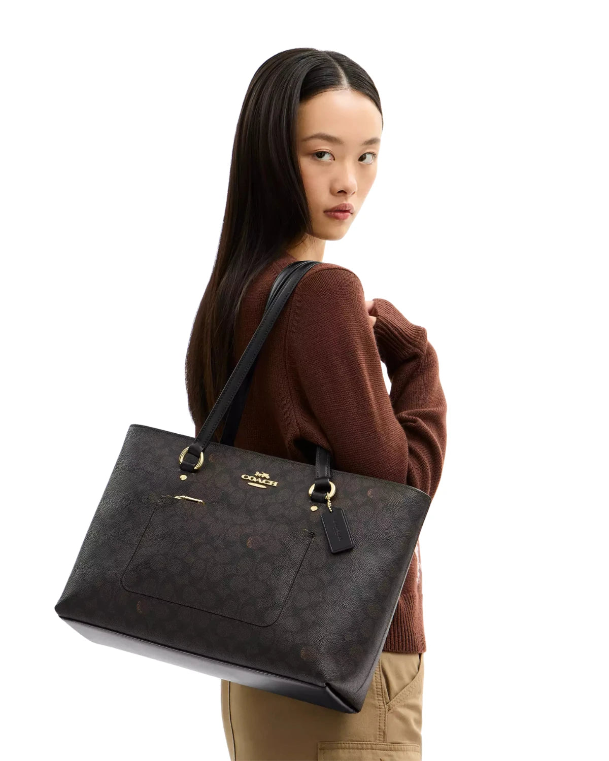 Woman carrying the Coach Station Tote Bag in Signature Canvas CCD69 on her shoulder, styled for work and everyday errands